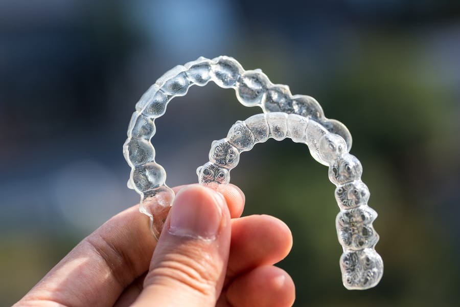 Ist Invisalign es wert? Klare Aligner im Licht halten.